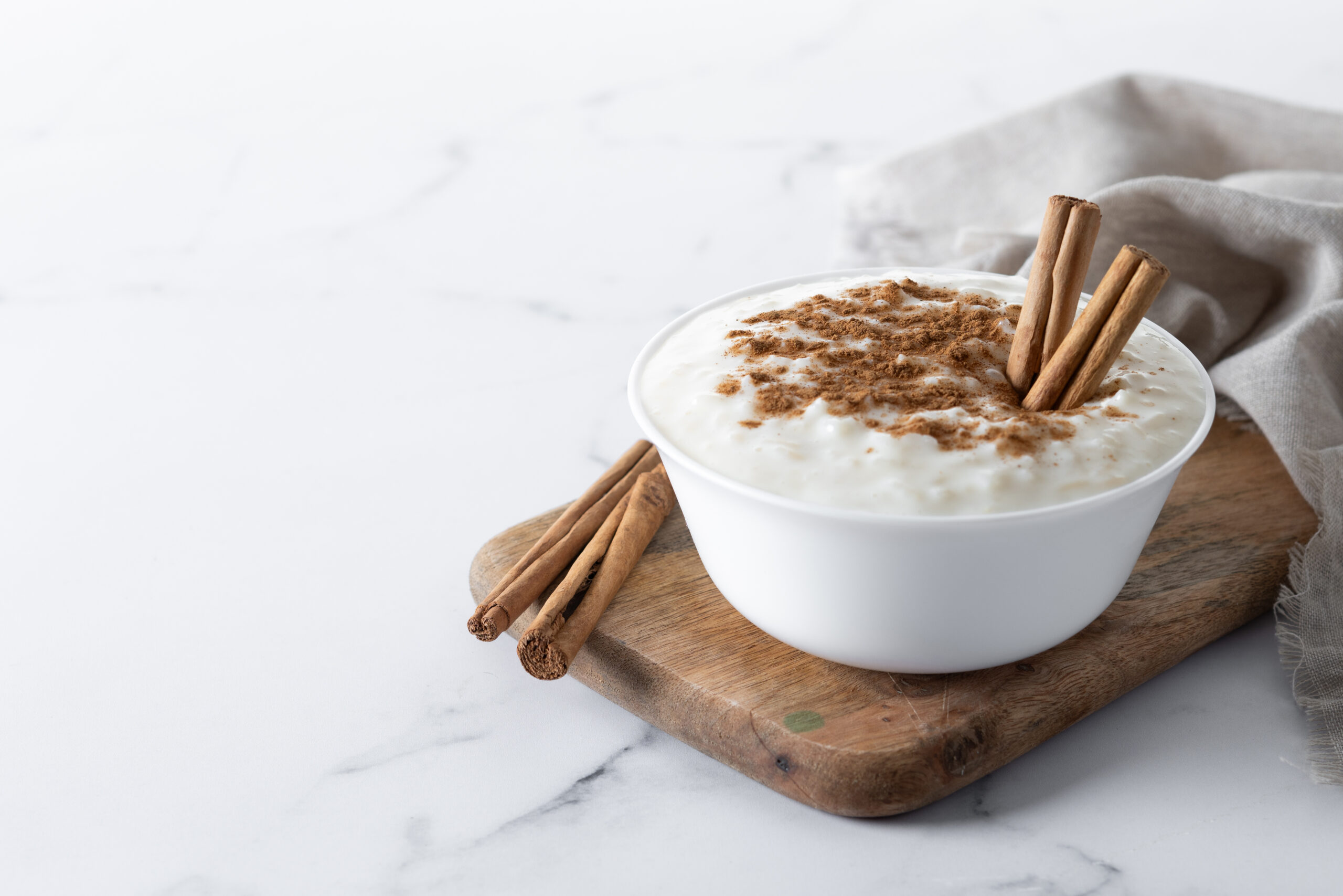 Arroz con leche. Rice pudding with cinnamon in clay bowl on white marble